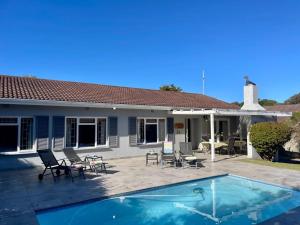 a house with a swimming pool and a patio at Beach House on Pachena in Plettenberg Bay