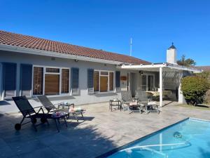 a patio with chairs and a pool and a house at Beach House on Pachena in Plettenberg Bay