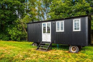 a black tiny house on wheels in a field at Berry Brook in Oakengrove Vineyard in Fawley