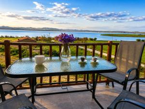 a glass table on a balcony with a vase of flowers at TERRA LEMNIA in Moúdhros