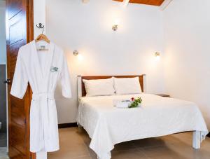 a white robe is hanging next to a bed at Lagoon Village B&B y SPA in Tarapoto +76 photos