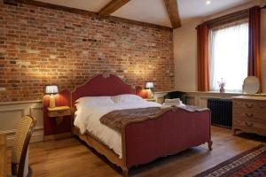 a bedroom with a large bed with a brick wall at The Dirty Habit in Hollingbourne