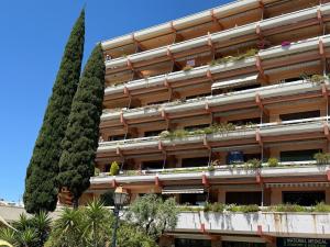 a building with two tall trees in front of it at T2 "Bohême" vue mer, centre ville tout à pied in Le Lavandou