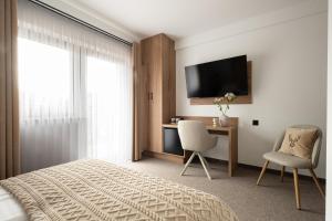 a bedroom with a bed and a desk and a television at Willa Lasak - 20 procent zniżki na Termy, Śniadania in Biały Dunajec
