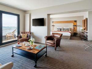 a hotel room with a bed and a living room at Côte Ouest Thalasso & Spa Les Sables d'Olonne - MGallery Collection in Les Sables-d'Olonne