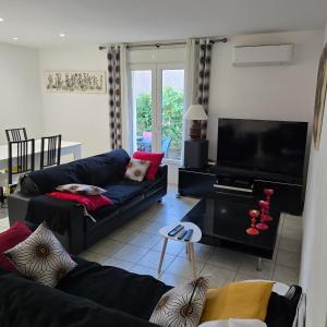 a living room with two couches and a flat screen tv at Maison Lauret in Agde
