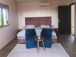 a bedroom with a bed with blue chairs and a table at Villa khaddouj Marrakech in Marrakesh