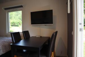 a dining room with a table and a television on the wall at Sjöstugan in Tyresö