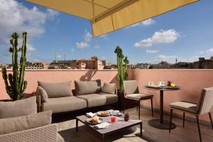 a patio with a couch and a table on a balcony at FH55 Grand Hotel Palatino in Rome