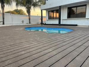 a house with a swimming pool on a wooden deck at Black Villa Lodge in Hammanskraal