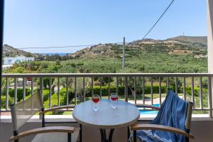 two glasses of wine sitting on a table on a balcony at Kassiani Studios Olive Groove hotel in Plakias