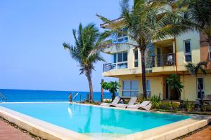 a swimming pool in front of a building with palm trees at Brisa Marina Beach Resort powered by Cocotel in Morong