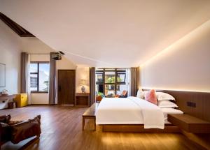a bedroom with a large white bed and wooden floors at 瓦述loft别院 in Zhangjiajie