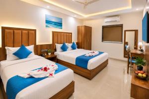 a hotel room with two beds and a flat screen tv at South Forest Wayanad By Bestinn Leisure in Sultan Bathery
