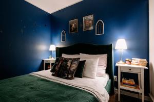 a bedroom with blue walls and a bed with pillows at Magiczny Salonik Harrego - Magical Old Town Apartment in Toruń