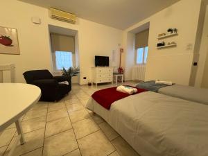a room with two beds and a chair and a table at In Bottega Apt 1 in Bosisio Parini