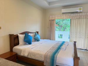 a bedroom with a bed with blue pillows and a window at Serene Resort Pattaya in Nong Prue