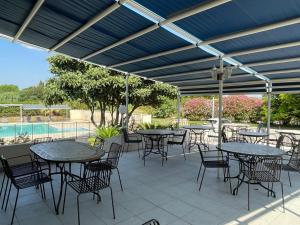 a patio with tables and chairs and a pool at Les Mimosas in Lunel