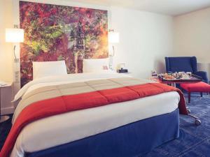 a bedroom with a large bed with a painting on the wall at Mercure Lille Marcq en Baroeul in Marcq-en-Baroeul +78 photos
