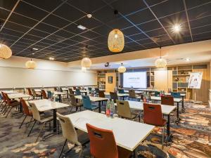 a dining room with tables and chairs and a screen at Mercure Lille Marcq en Baroeul in Marcq-en-Baroeul