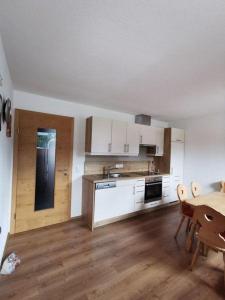 a kitchen with white cabinets and a table and a dining room at Apart Kröll in Schlitters
