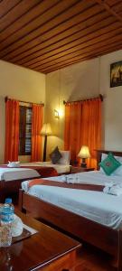 a hotel room with two beds and a table at Villa Saykham in Luang Prabang