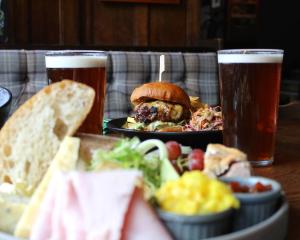 a table with a plate of food and two glasses of beer at Scotsman's Pack Hotel in Hathersage