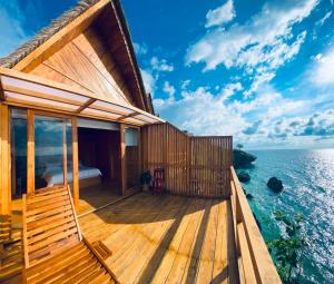 a house on the water with a deck at Aresona Cliff House in Bira