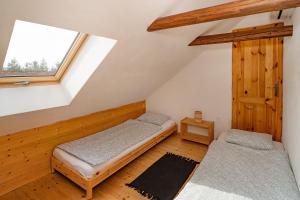 a attic room with two beds and a window at Apartmán Maštal in Osek