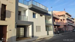 a white building with a balcony on the side of a street at Terra de Mari in Quartu SantʼElena