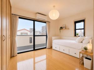 a bedroom with a bed and a large window at K2Guesthouse Konohana in Osaka