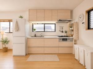 a kitchen with white cabinets and a white refrigerator at K2Guesthouse Konohana in Osaka