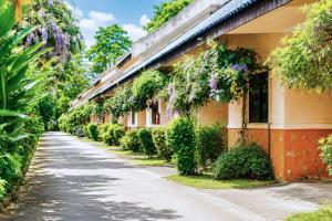 an empty street in front of a building with plants at Chalet De Palm Resort Hatyai in Hat Yai