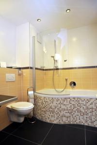 a bathroom with a shower and a toilet and a tub at Posthotel Traube in Donauwörth +25 photos