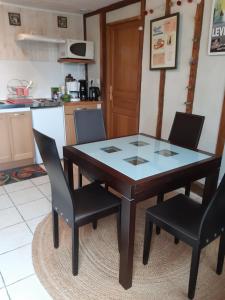 a dining room table with two chairs and a kitchen at La ferme sympa in Droyes
