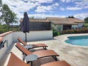 a patio with chairs and an umbrella next to a swimming pool at Gites Champfort in Saint-Vallier