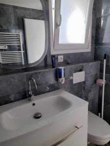 a bathroom with a sink and a mirror and a toilet at Césaria in Loupian