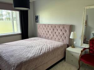 a bedroom with a pink bed and a red chair at Rofabær 45 in Reykjavík