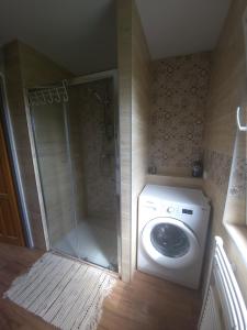 a bathroom with a shower and a washing machine at Chata u lesa in Divec