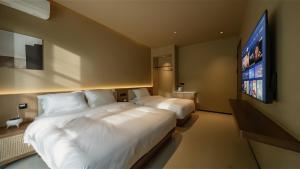 a hotel room with two beds and a flat screen tv at Qinxiang Pavilion Hotel in Dunhuang