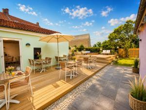 eine Holzterrasse mit Tischen, Stühlen und einem Sonnenschirm in der Unterkunft Stub Inn Guesthouse in Stubbekøbing