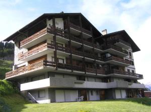 ein großes Gebäude mit Balkonen auf einem Hügel in der Unterkunft Le Panorama - Appartement 54 à Arolla face aux montagnes à 150m des pistes in Evolène