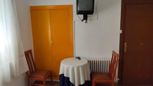 a room with a table and a yellow door and a tv at Hostal Restaurante Moderno in Cistierna