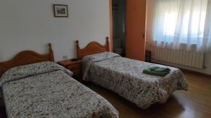 two beds in a hotel room with two green towels on them at Hostal Restaurante Moderno in Cistierna