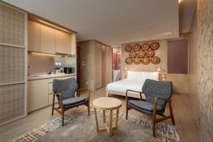 a hotel room with a bed and two chairs and a table at Hotel Madera Hong Kong in Hong Kong