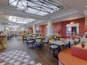 a restaurant with tables and chairs in a room at Mercure Lyon Est Villefontaine in Villefontaine