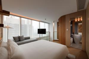 a bedroom with a bed and a couch and a television at Hotel Madera Hong Kong in Hong Kong