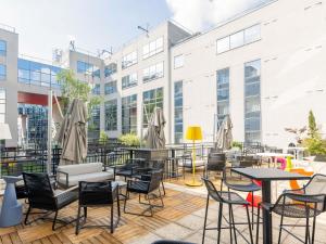 an outdoor patio with tables and chairs and buildings at Mercure Paris Massy Gare TGV in Massy