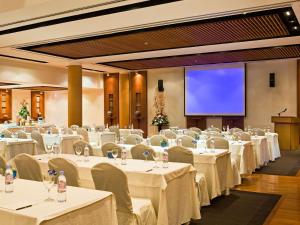 a conference room with white tables and chairs and a screen at Sofitel Mauritius L'Imperial Resort & Spa in Flic-en-Flac +147 photos