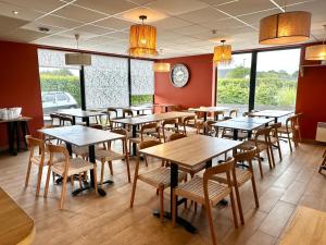 a restaurant with wooden tables and chairs and windows at Best Western Hotel de la plage Normandie in Asnelles